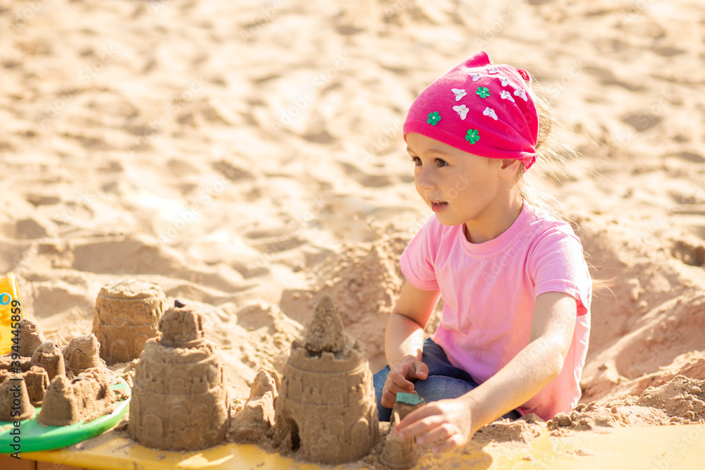 Small cute girl shares a sand castle in a sandbox Small cute girl shares a sand castle in a sandbox