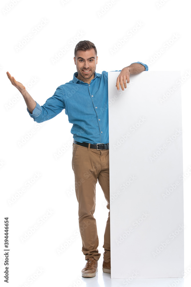 handsome casual man leaning on a long billboard and smiling handsome casual man leaning on a long billboard and smiling