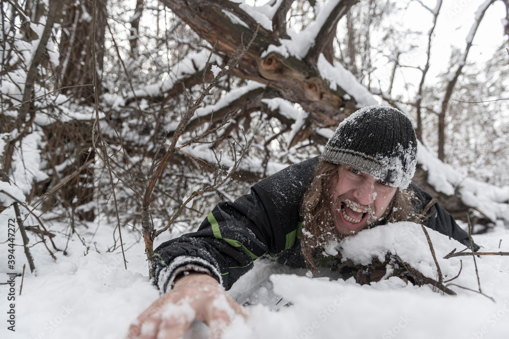 Man under a fallen tree struggles for his life in the winter forest.