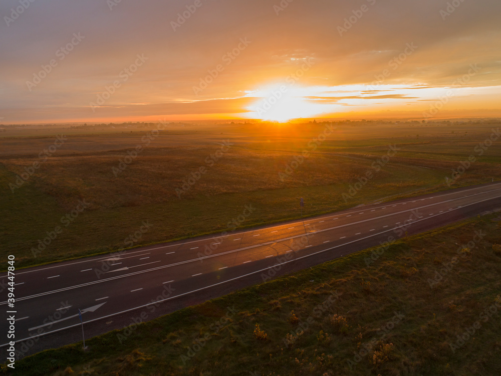 Marking on a new road in the evening on a background of sunset, countryside fields.