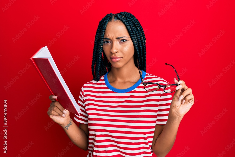 Beautiful hispanic woman reading a book with glasses skeptic and nervous, frowning upset because of problem. negative person. Beautiful hispanic woman reading a book with glasses skeptic and nervous, frowning upset because of problem. negative person.