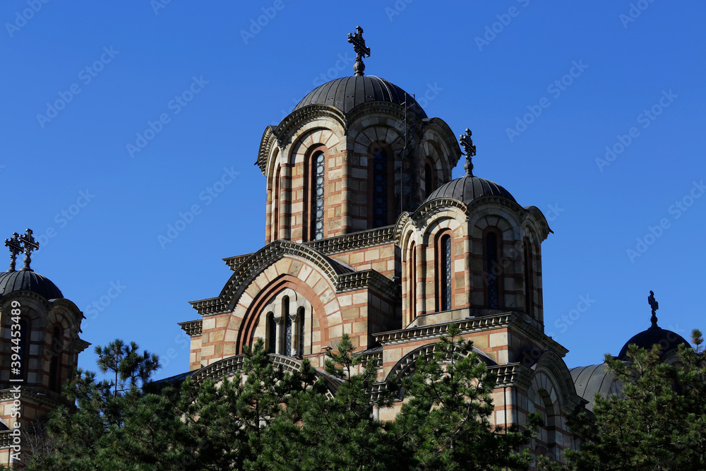 Front view of St. Mark's orthodox church amid trees in Tasmajdan park, during a sunny autumn day in Belgrade, Serbia.