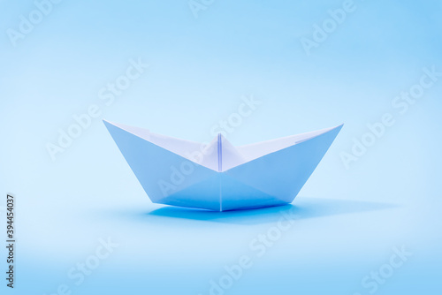 White paper boat on a blue background  a boat floating on the water  a symbol of hope  origami  classic blue of the year