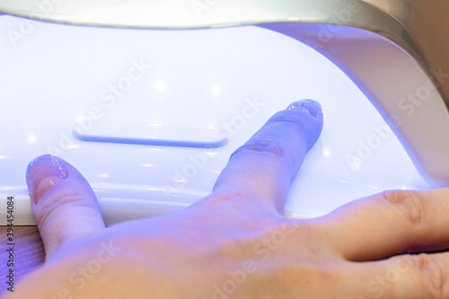 Drying nails after applying varnish in a special ultraviolet dryer