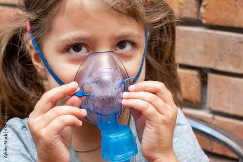 Little girl doing inhalation procedure at home using a mask