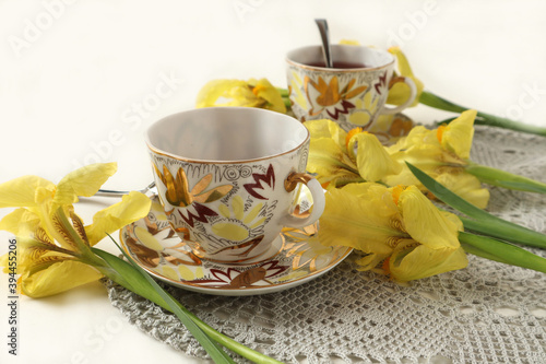 Yellow irises with two cups of tea on a gray napkin  side view  space for text-the concept of pleasant meetings and a wonderful time