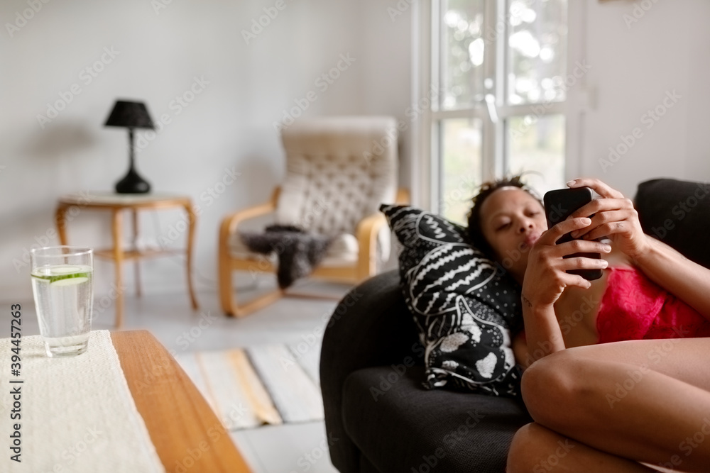 Woman on sofa using cell phone, Sweden Woman on sofa using cell phone, Sweden