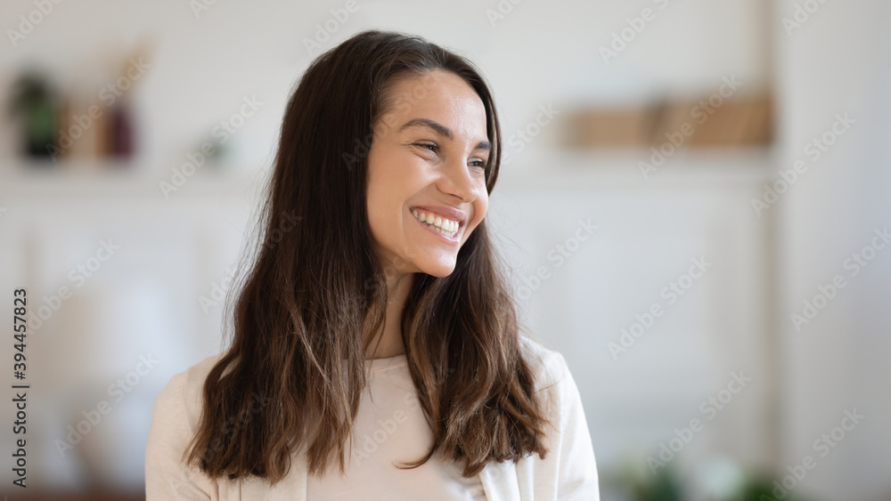 Full of joy. Overjoyed millennial woman standing indoors laughing having fun looking aside feeling happy carefree motivated, cheerful young lady client of dental clinic demonstrating white shiny smile