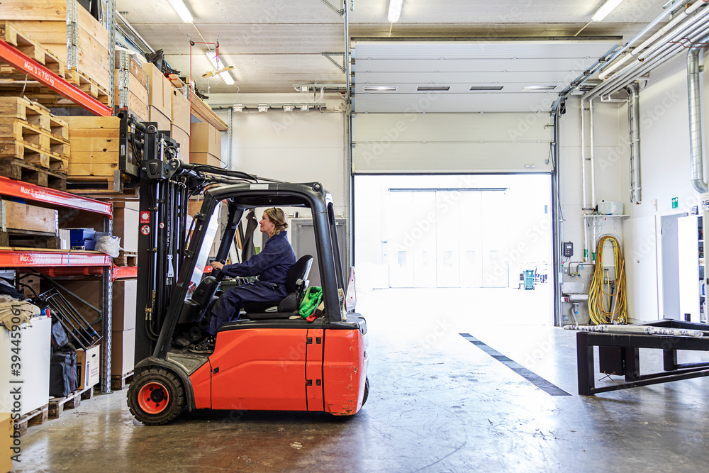 Woman driving forklift truck in warehouse, Sweden Woman driving forklift truck in warehouse, Sweden