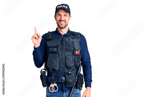 Young handsome man wearing police uniform with a big smile on face, pointing with hand finger to the side looking at the camera.