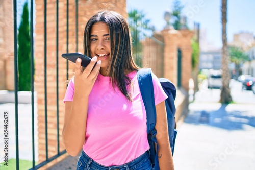 Young latin student girl sending audio message using smartphone at university campus. © Krakenimages.com