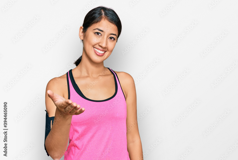 Beautiful asian young sport woman wearing sportswear and arm band smiling friendly offering handshake as greeting and welcoming. successful business. Beautiful asian young sport woman wearing sportswear and arm band smiling friendly offering handshake as greeting and welcoming. successful business.