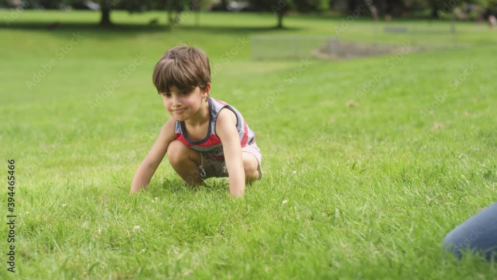 A young boy eats a bubble sitting on the grass at the park A young boy eats a bubble sitting on the grass at the park