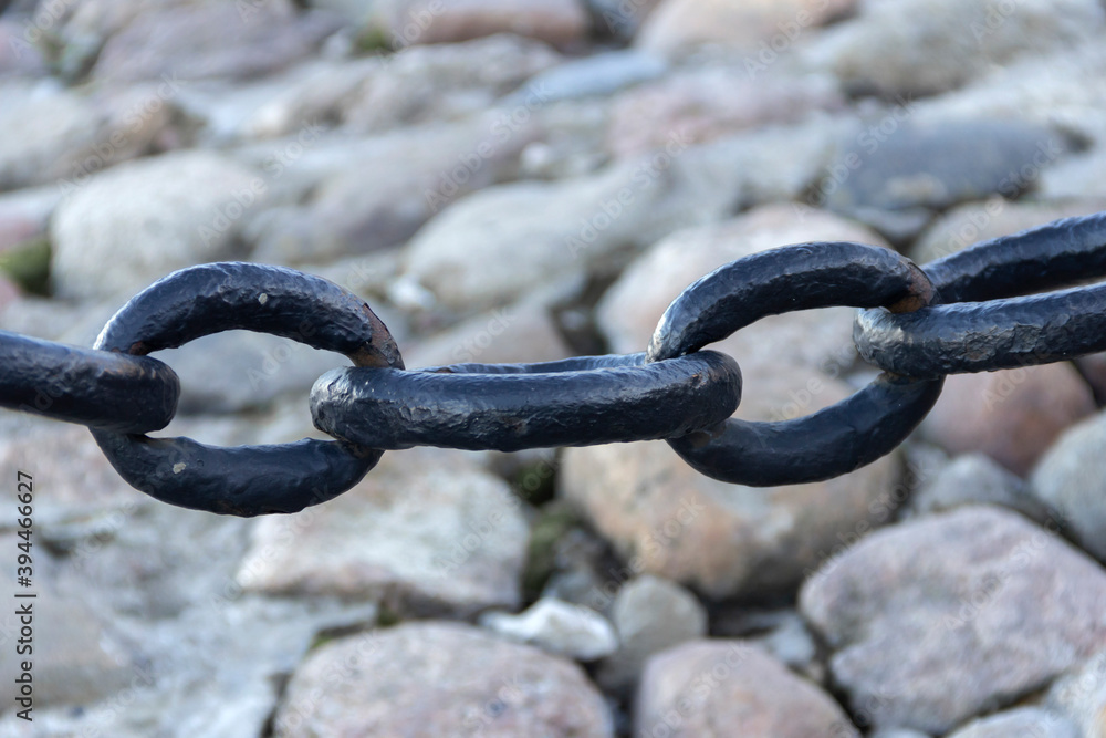 Old forged rusty chain with peeling paint on the background of paving stones. Old forged rusty chain with peeling paint on the background of paving stones.
