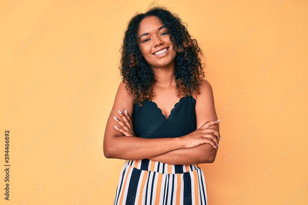 Young african american woman wearing casual clothes happy face smiling with crossed arms looking at the camera. positive person. Young african american woman wearing casual clothes happy face smiling with crossed arms looking at the camera. positive person.
