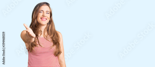 Beautiful caucasian young woman wearing casual clothes smiling friendly offering handshake as greeting and welcoming. successful business.