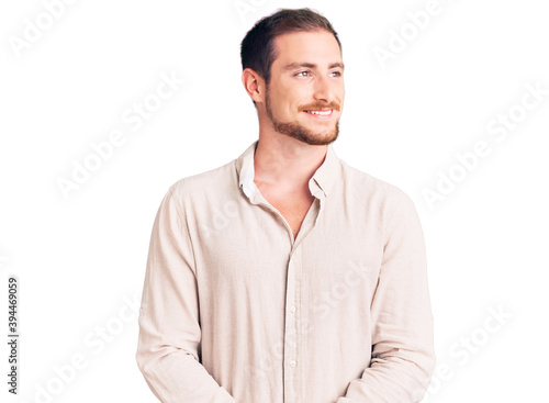 Young handsome caucasian man wearing casual clothes looking away to side with smile on face, natural expression. laughing confident.