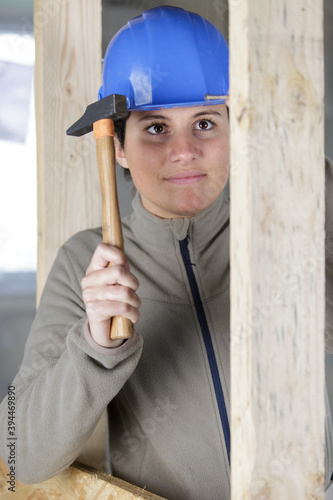 joyful builder smiling and hammering a nail into the wall