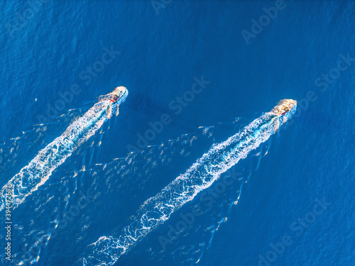 Aerial view of two fishing boats in the sea at sunset in summer. Colorful landscape with moving motorboats. Top view from drone of floating yachts in ocean. Travel. Beautiful seascape