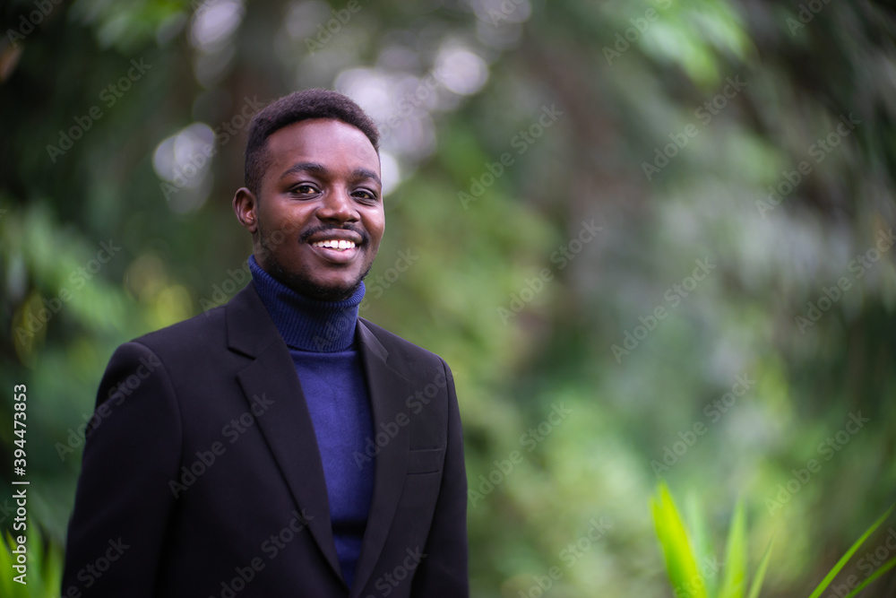 Handsome african business man in trendy formal black suit. Guy with beard wearing blue long sleeve or sweater Handsome african business man in trendy formal black suit. Guy with beard wearing blue long sleeve or sweater