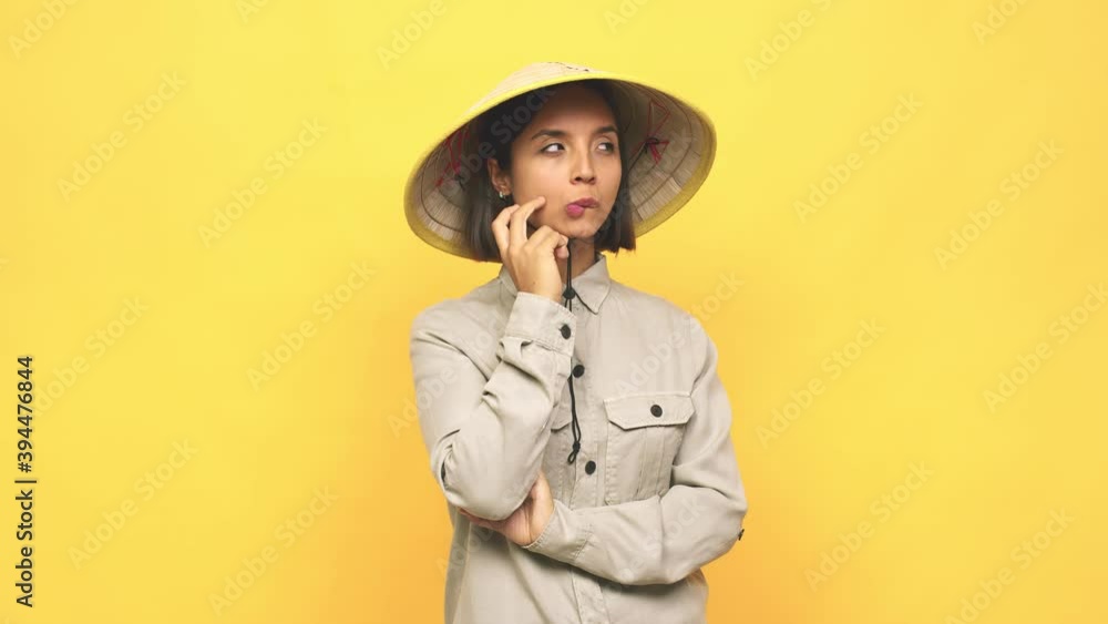 Young latin woman with vietnamite hat confused, feels doubtful and unsure Young latin woman with vietnamite hat confused, feels doubtful and unsure
