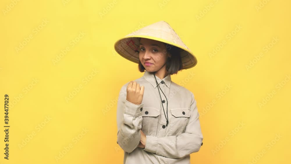 Young latin woman with vietnamite hat pointing with finger at you as if inviting come closer Young latin woman with vietnamite hat pointing with finger at you as if inviting come closer