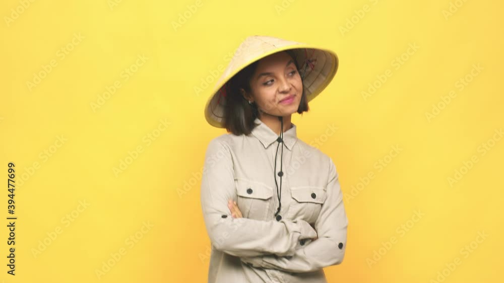 Young latin woman with vietnamite hat smiling with arms crossed Young latin woman with vietnamite hat smiling with arms crossed