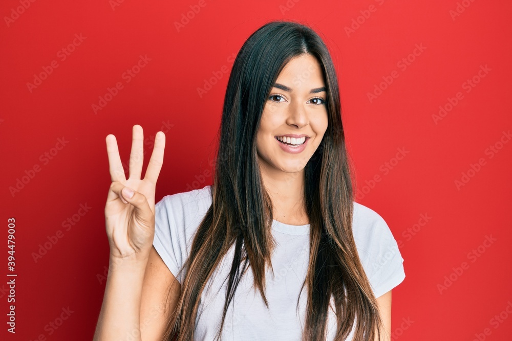 Young brunette woman wearing casual white tshirt over red background showing and pointing up with fingers number three while smiling confident and happy. Young brunette woman wearing casual white tshirt over red background showing and pointing up with fingers number three while smiling confident and happy.
