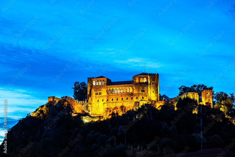 Skyline of the castle of Leiria on a hill top surrounded by trees and buildings in the old town of Leiria, Portugal