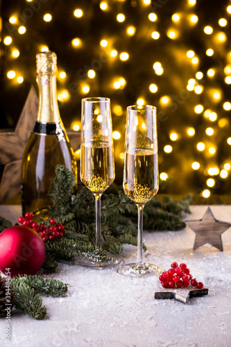 Two glasses of sparkling champagne at New year eve night with clock and bokeh background. Christmas decoration dinner table setting, copy space