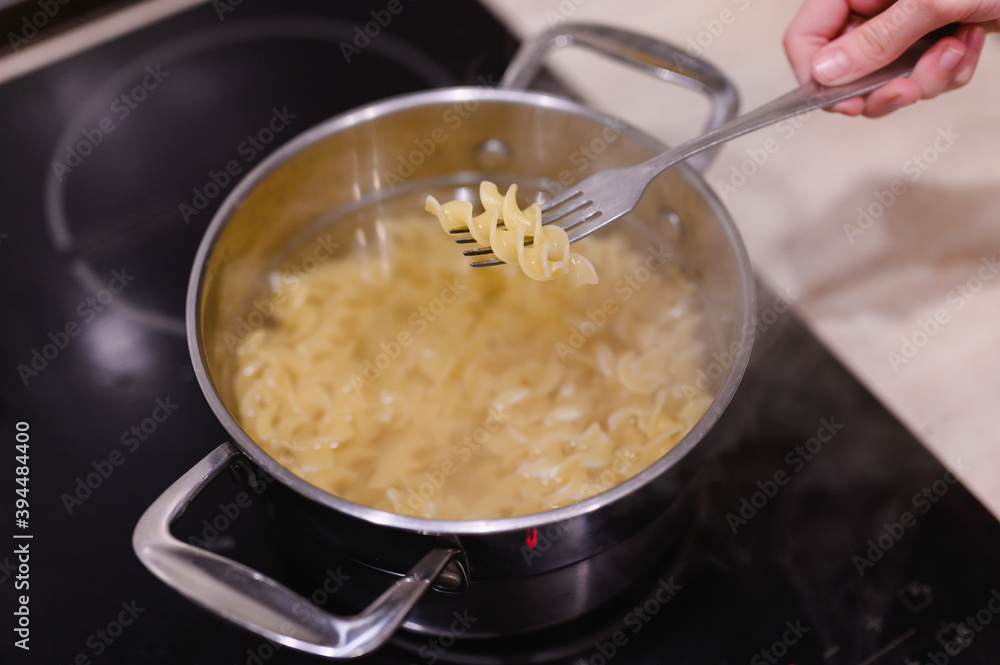 Pasta on a fork over a pot of boiling water and pasta. The process of cooking pasta at home. Pasta on a fork over a pot of boiling water and pasta. The process of cooking pasta at home.