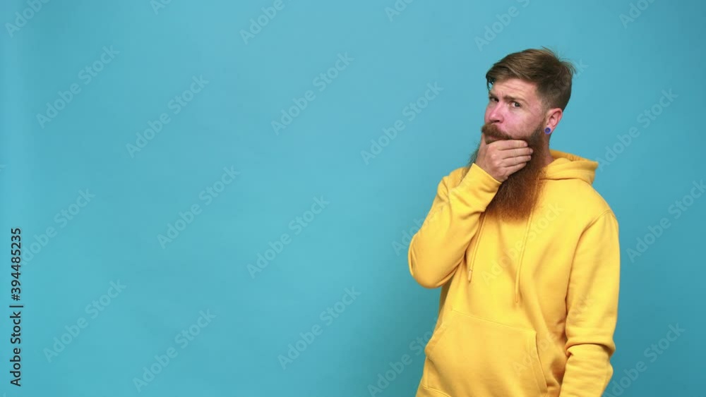 Young adult bearded caucasian man isolated thoughtful looking to a copy space covering mouth with hand Young adult bearded caucasian man isolated thoughtful looking to a copy space covering mouth with hand
