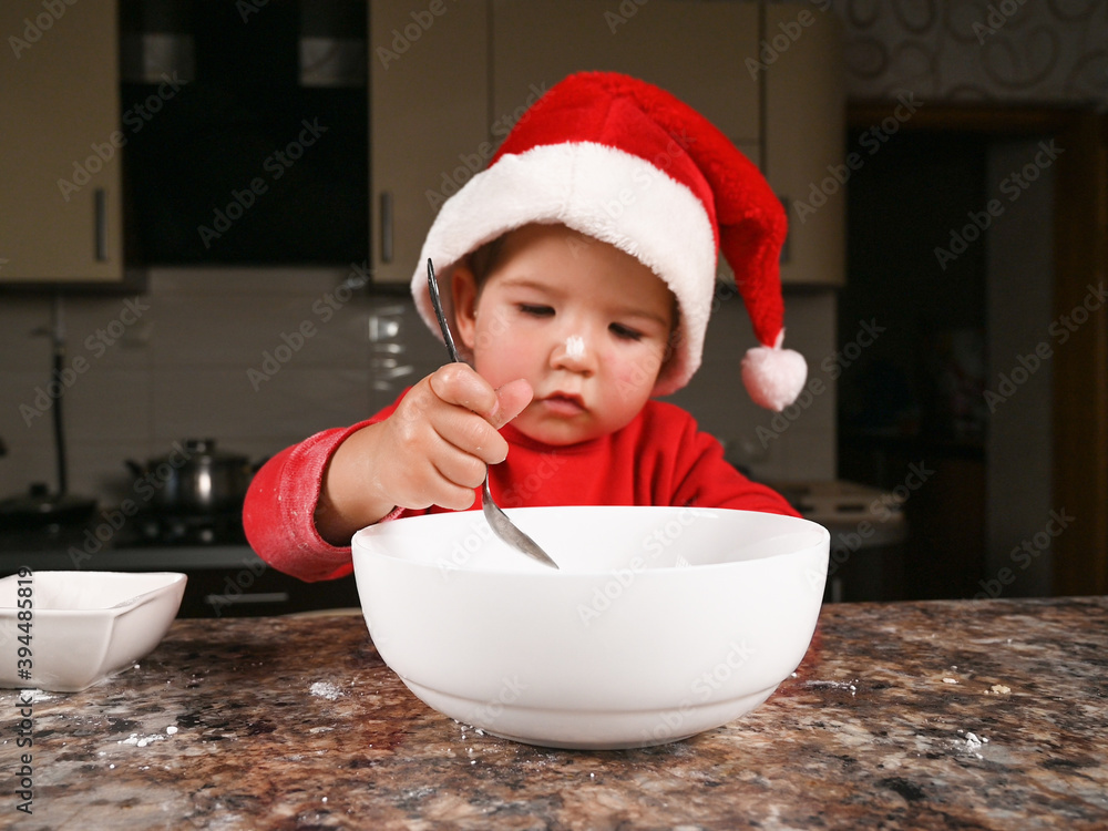 A child in a Christmas hat is preparing a New Year's dinner A child in a Christmas hat is preparing a New Year's dinner