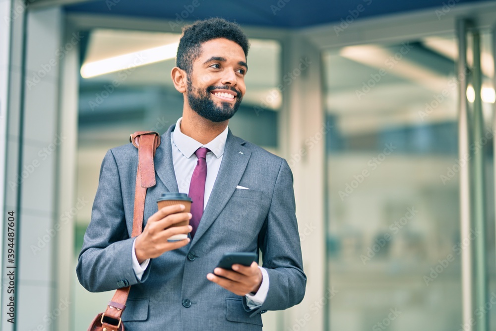 Young african american businessman using smartphone and drinking take away coffee at the city. Young african american businessman using smartphone and drinking take away coffee at the city.