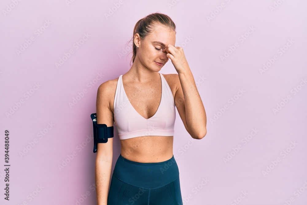 Beautiful blonde woman wearing sportswear and arm band tired rubbing nose and eyes feeling fatigue and headache. stress and frustration concept. Beautiful blonde woman wearing sportswear and arm band tired rubbing nose and eyes feeling fatigue and headache. stress and frustration concept.