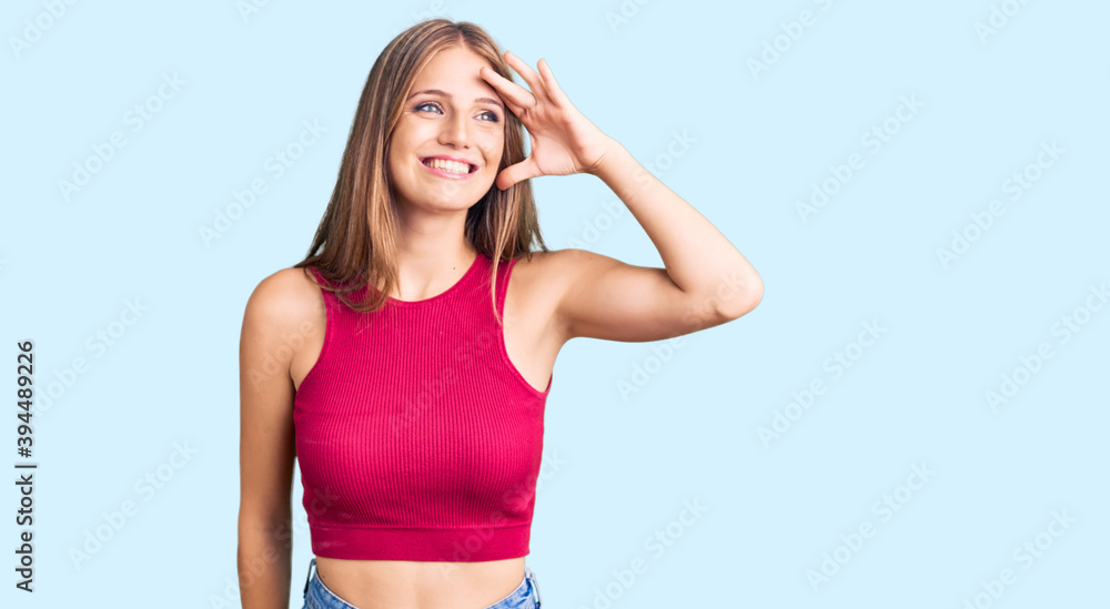 Young beautiful blonde woman wearing elegant summer shirt very happy and smiling looking far away with hand over head. searching concept. Young beautiful blonde woman wearing elegant summer shirt very happy and smiling looking far away with hand over head. searching concept.