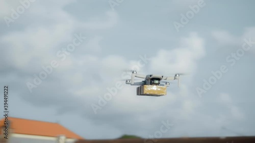 flying on a sky delivery drone with holding a .cardboard parcel photo