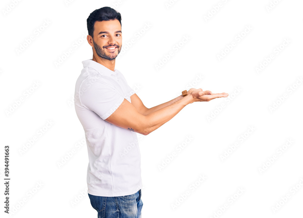 Young handsome hispanic man wearing casual clothes pointing aside with hands open palms showing copy space, presenting advertisement smiling excited happy Young handsome hispanic man wearing casual clothes pointing aside with hands open palms showing copy space, presenting advertisement smiling excited happy