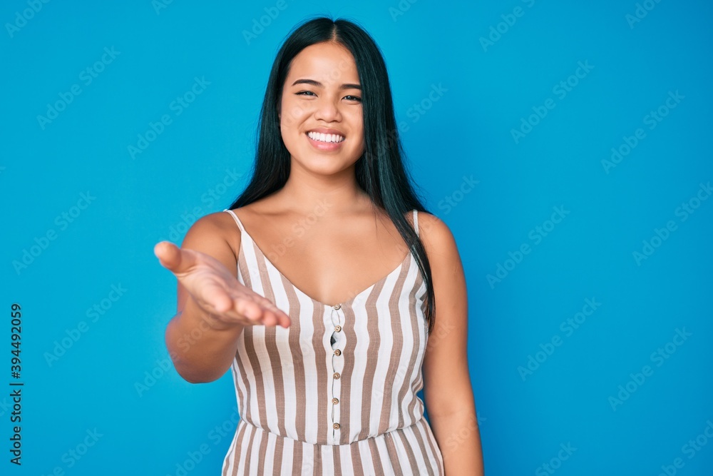 Young beautiful asian girl wearing casual clothes smiling friendly offering handshake as greeting and welcoming. successful business.