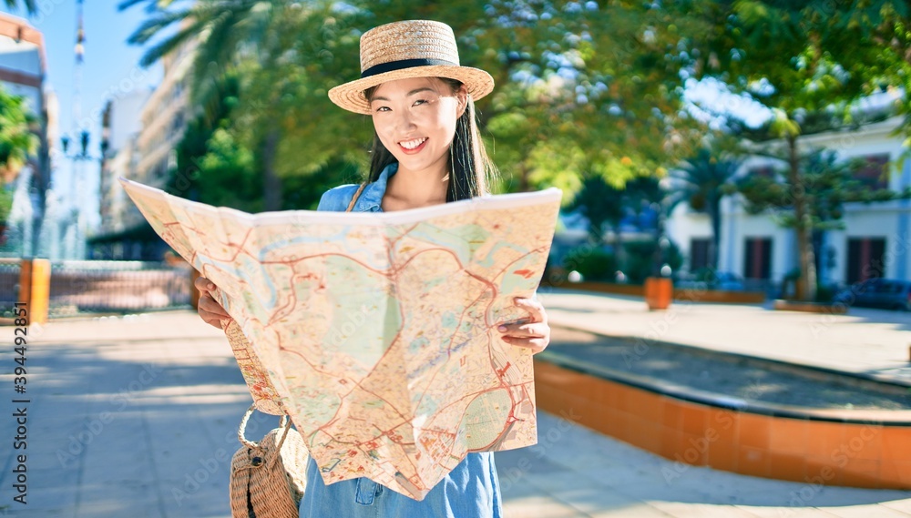 Fototapeta premium Young chinese tourist woman smiling happy holding city map at the park.