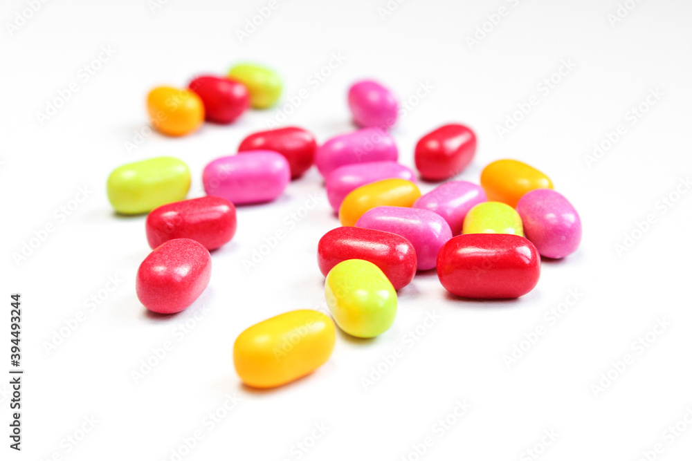 Small pill drops scattered on white surface. Pile of colorful bean shaped candies Small pill drops scattered on white surface. Pile of colorful bean shaped candies