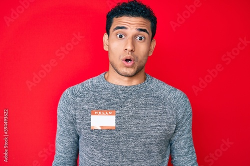Canvas Print Young handsome hispanic man wearing hello my name is sticker identification scar