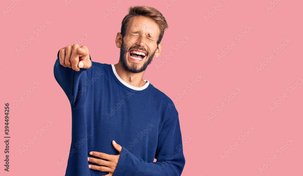 Handsome blond man with beard wearing casual sweater laughing at you, pointing finger to the camera with hand over body, shame expression Handsome blond man with beard wearing casual sweater laughing at you, pointing finger to the camera with hand over body, shame expression