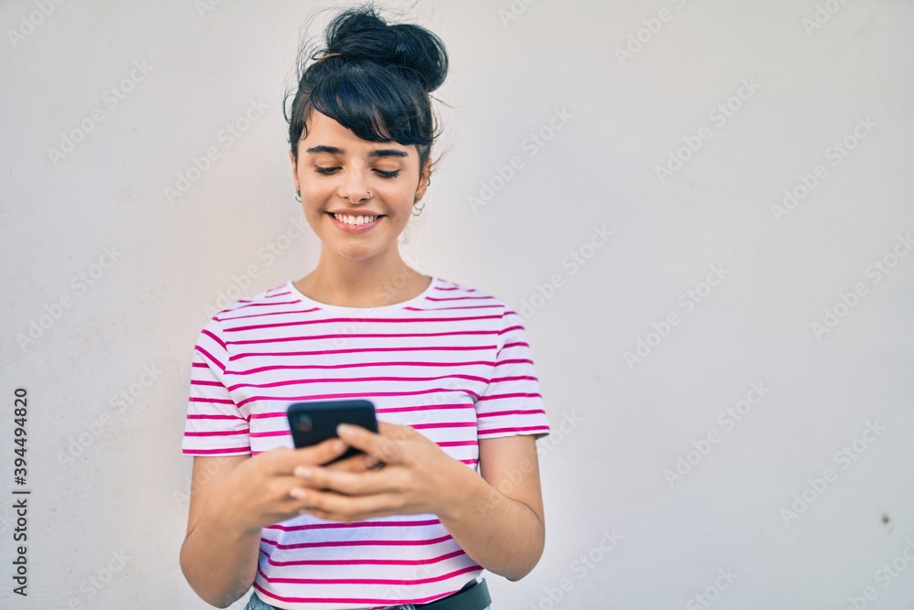 Young hispanic girl smiling happy using smartphone at the city. Young hispanic girl smiling happy using smartphone at the city.