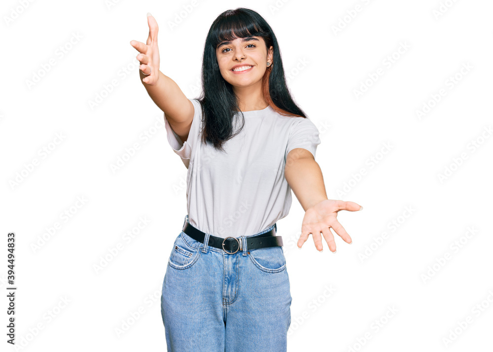 Young hispanic girl wearing casual clothes looking at the camera smiling with open arms for hug. cheerful expression embracing happiness. Young hispanic girl wearing casual clothes looking at the camera smiling with open arms for hug. cheerful expression embracing happiness.
