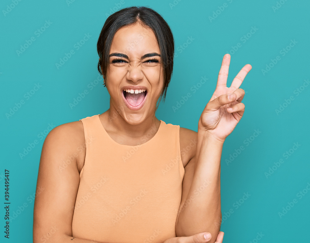 Young brunette woman wearing casual clothes smiling with happy face winking at the camera doing victory sign. number two. Young brunette woman wearing casual clothes smiling with happy face winking at the camera doing victory sign. number two.