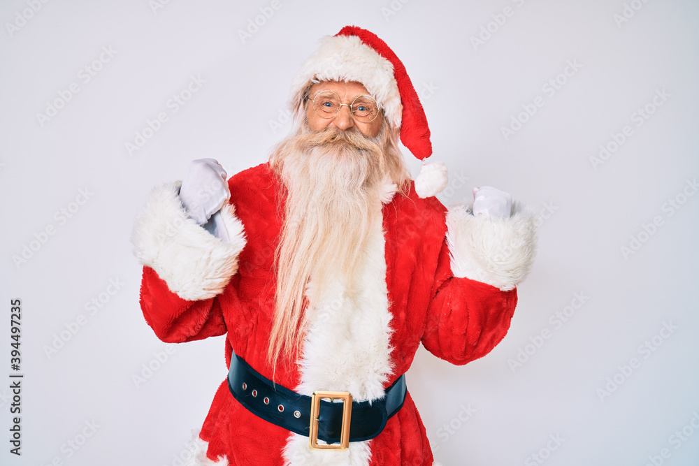 Old senior man with grey hair and long beard wearing santa claus costume with suspenders excited for success with arms raised and eyes closed celebrating victory smiling. winner concept.