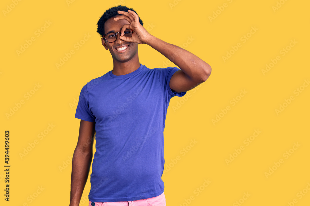 African handsome man wearing casual clothes and glasses doing ok gesture with hand smiling, eye looking through fingers with happy face. African handsome man wearing casual clothes and glasses doing ok gesture with hand smiling, eye looking through fingers with happy face.