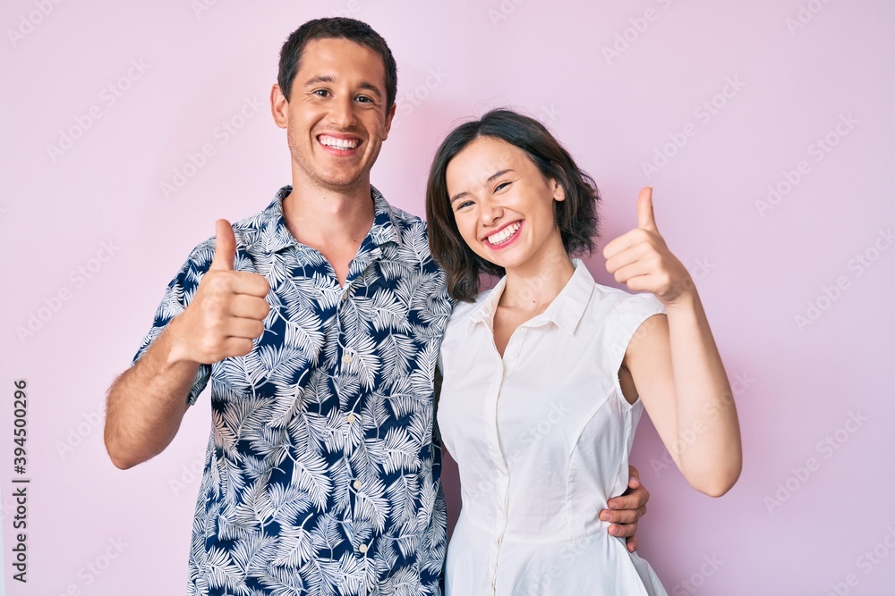 Beautiful couple wearing casual clothes doing happy thumbs up gesture with hand. approving expression looking at the camera showing success. Beautiful couple wearing casual clothes doing happy thumbs up gesture with hand. approving expression looking at the camera showing success.