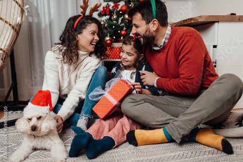 Young father, mother and daughter celebrating New year at their home. Festive family indoors concept.